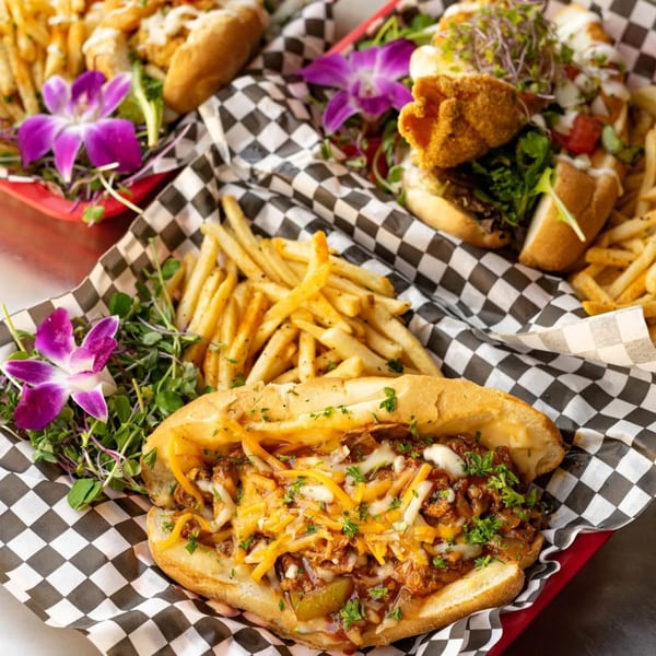Two Po' Shines Cafe De La Soul po'boy sandwiches with fries and purple orchid garnishes.