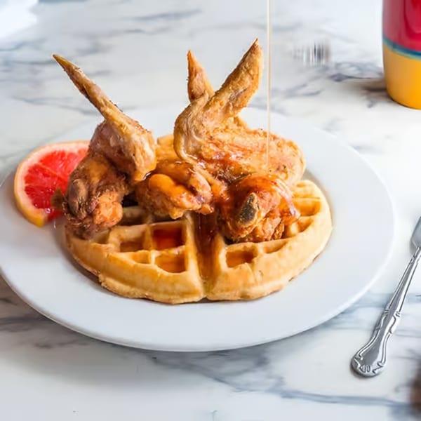 Po' Shines Cafe De La Soul's chicken and waffles with syrup and a grapefruit slice.